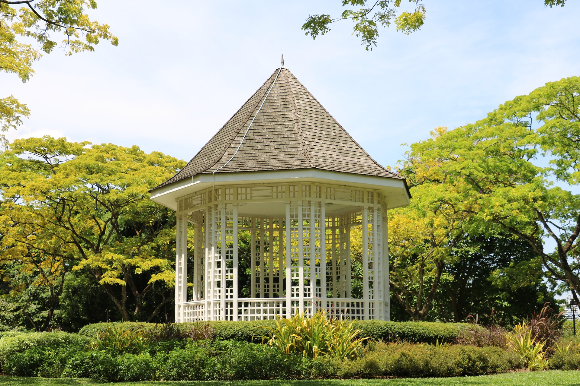 Landscaping and lawn with white gazebo, green trees, and shrubs.