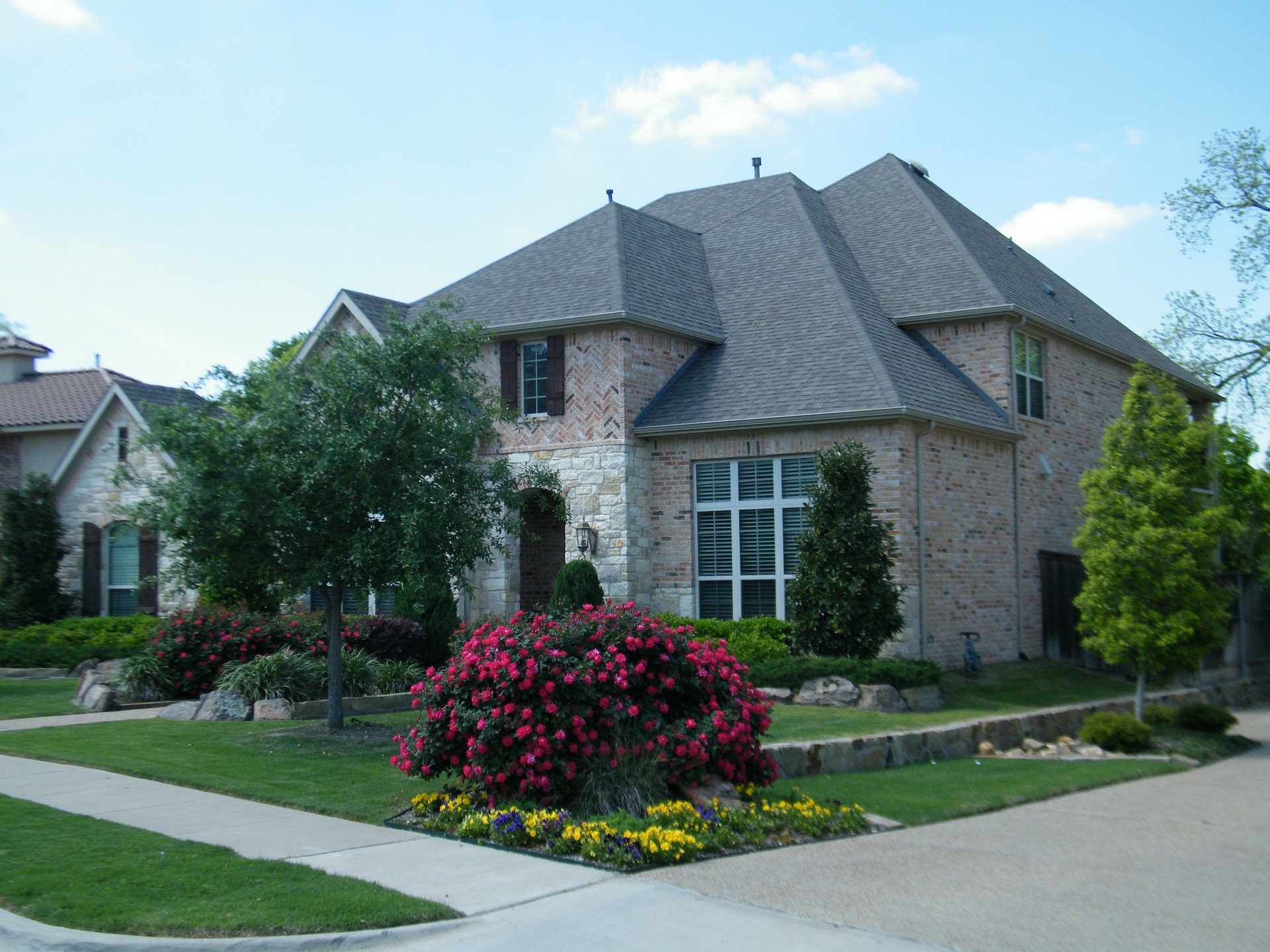 Brick house with landscaping including lawn, red roses, and yellow flowers