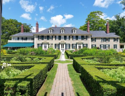 Expansive yard with boxwood hedges and pavers demonstrating a high landscaping cost.