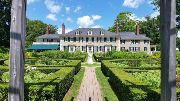 Expansive yard with boxwood hedges and pavers demonstrating a high landscaping cost.