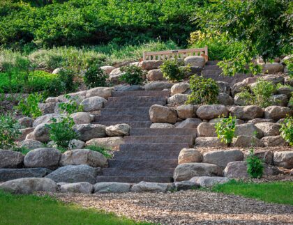 Knowing the basics of how to landscape a slope yields creative results like this mix-and-match boulder and slab terrace.