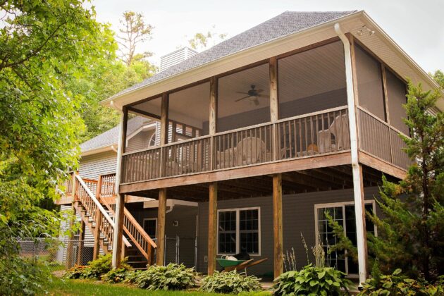 This home utilizes the best of deck landscaping tips with a screened in back porch, ceiling fan for hot summer nights, and plants that soften the borders of the hardscape.